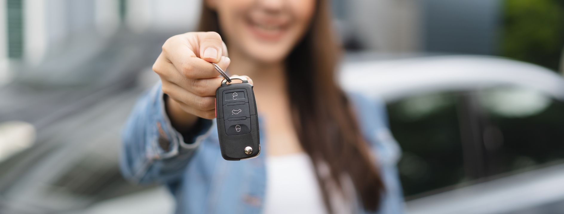 Smiling young woman handing in the keys to her vehicle