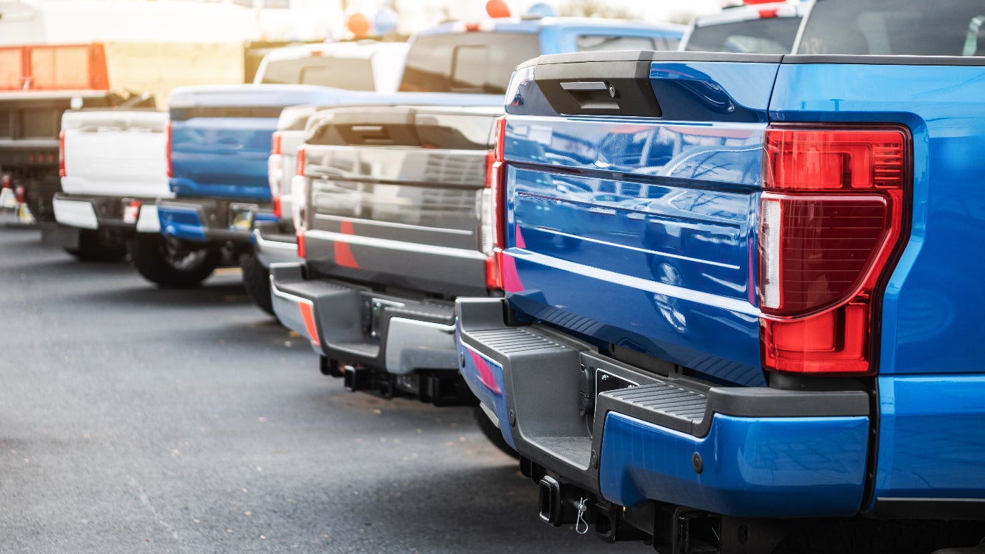 A rear view of a row of trucks in a parking lot.
