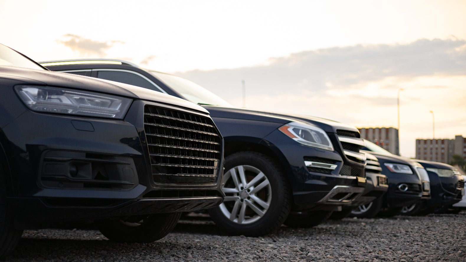 A row of dark-colored SUVs parked on a dealership lot.