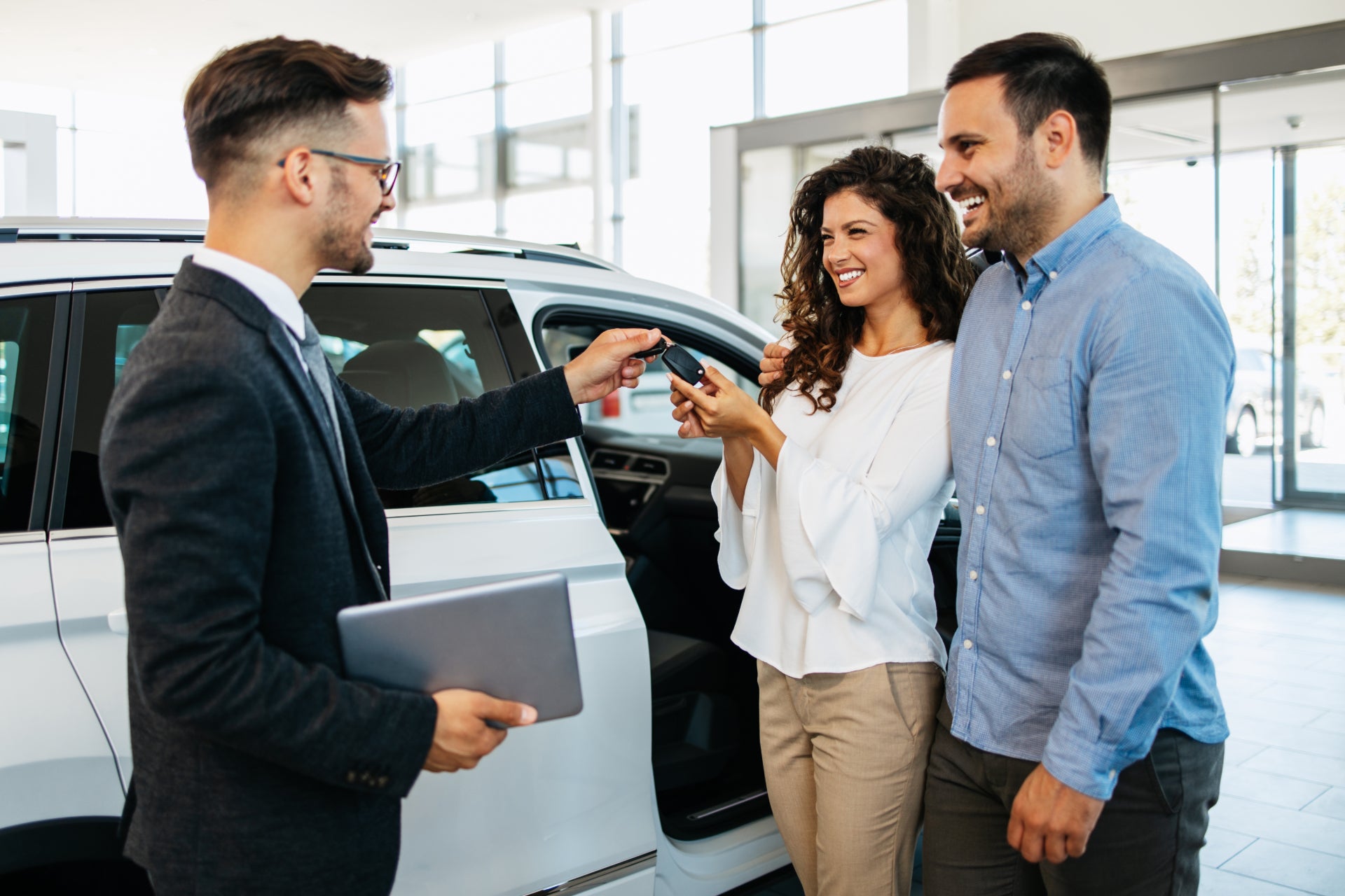 Smiling couple getting the keys to their next used vehicle