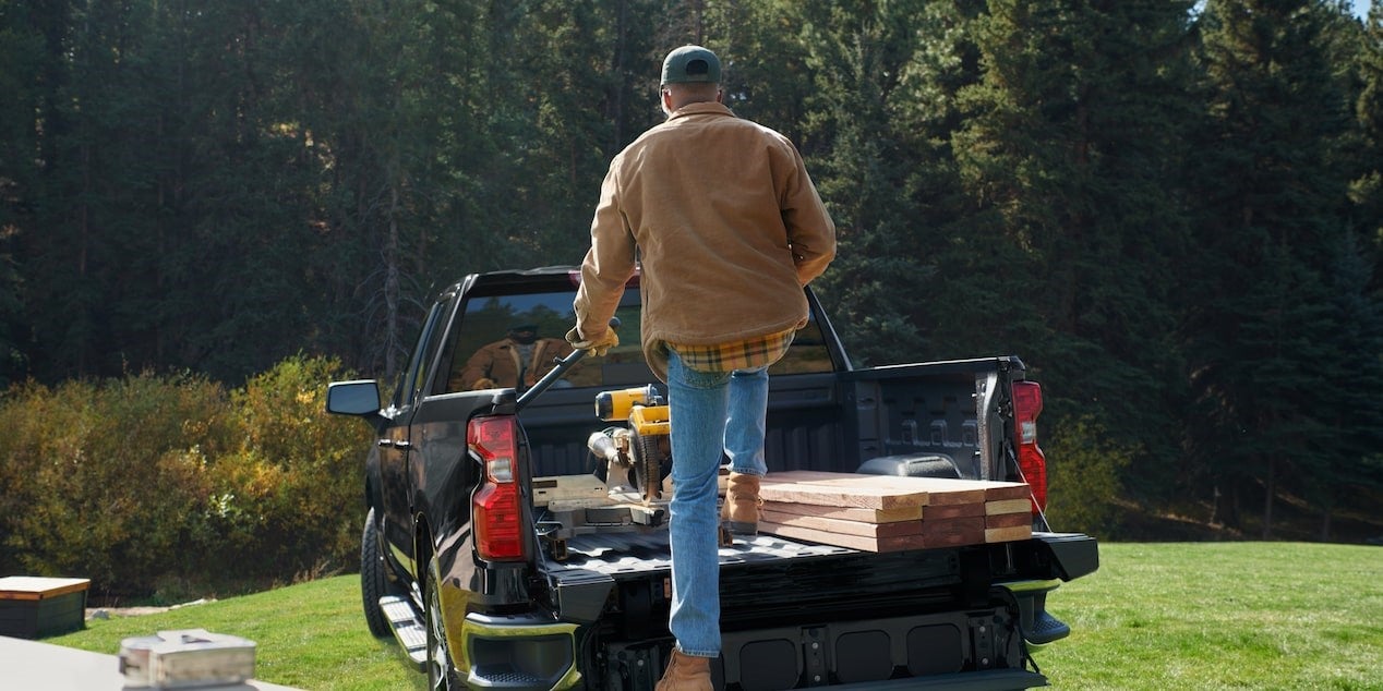 Man stepping into the bed of his pre-owned truck
