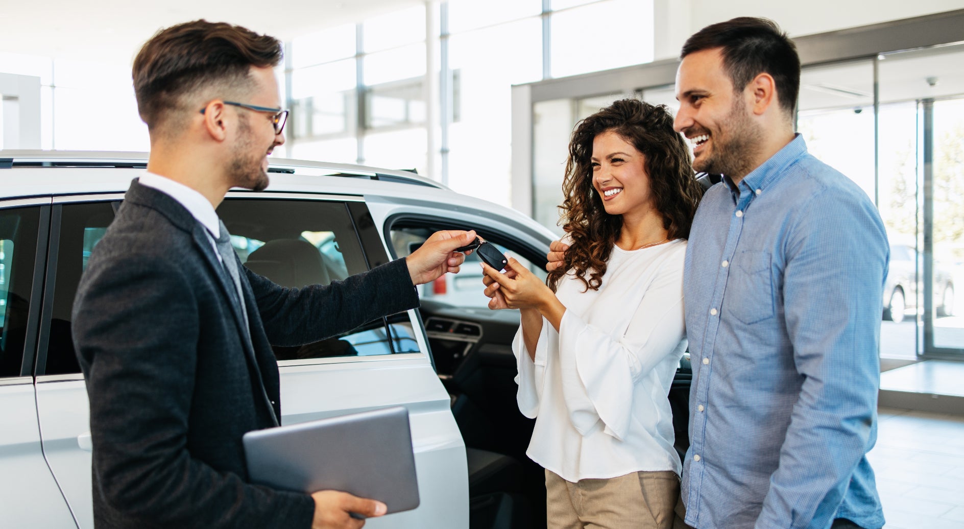 Young couple getting the keys to their used vehicle