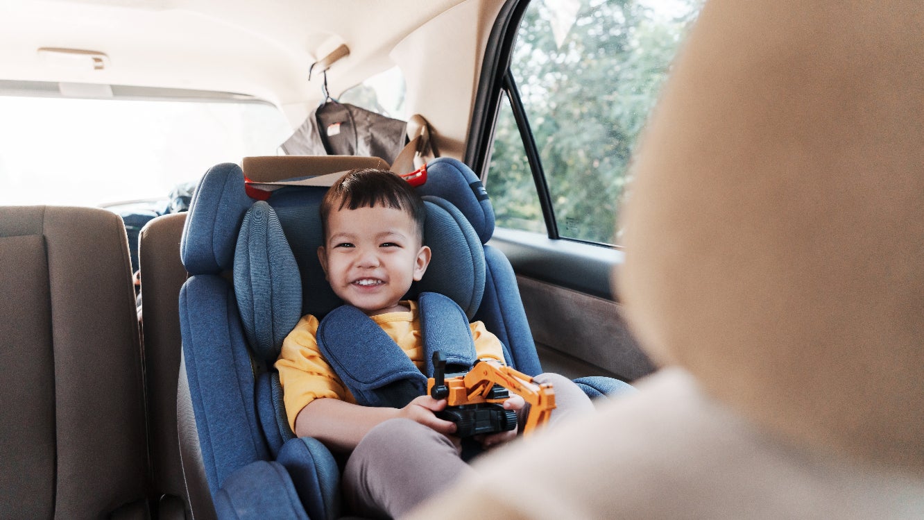 A child smiling while sitting in a car seat.